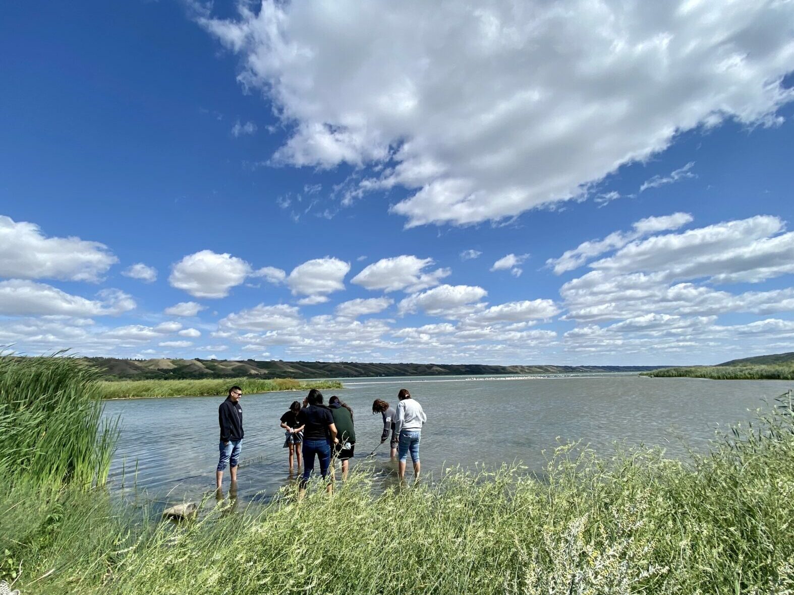 A group of youth are seen testing the water at an inlet of a River in Saskatchewan.